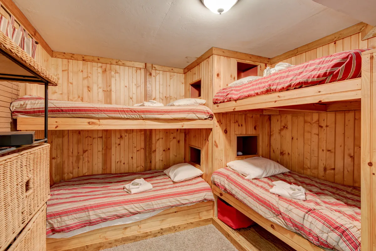 A welcoming children's bunk room with wooden paneling, sturdy bunk beds, and convenient storage baskets. The playful yet organized space is designed for storytelling, playtime, and restful sleep for younger guests.