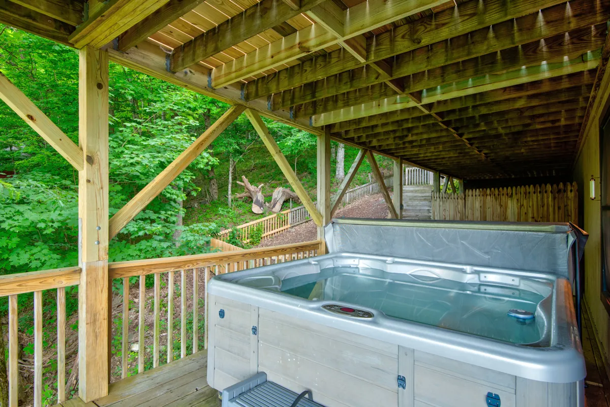 This image features a serene hot tub set on a wooden deck surrounded by lush greenery. The hot tub is the focal point, inviting relaxation and connection to the natural world outside. The surrounding foliage and tranquil ambiance evoke the feeling of a private mountain sanctuary.